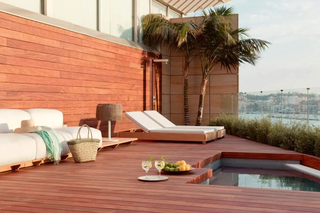 Terrasse mit Liegestühlen, kleinem Pool und Palmen.