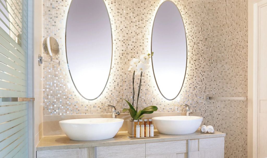 Luxuriöses Badezimmer mit zwei ovalen Spiegeln, Waschbecken und Dekoration.