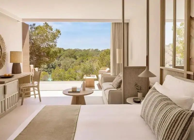 Helles Zimmer mit Doppelbett und Blick auf grüne Landschaft von Balkon