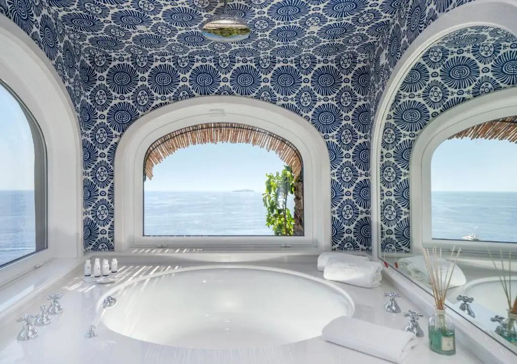 Luxuriöses Badezimmer mit Rundbadewanne und blauem Fliesenmuster sowie Meerblick