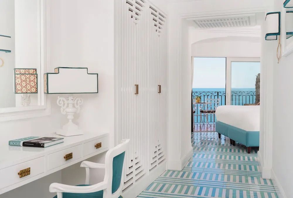 Helles Zimmer mit Schreibtisch und Schrank, Ausblick auf Meer und Balkon.