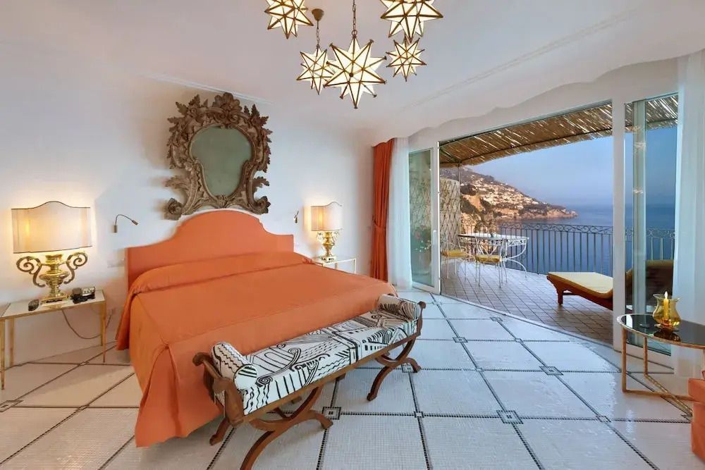 Luxuriöses Zimmer mit orangem Bettbezug und Meerblick von der Terrasse