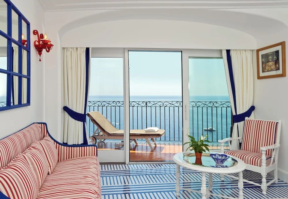 Helles Zimmer mit Meerblick und Balkon. Stilvolle Einrichtung mit gestreifter Couch.