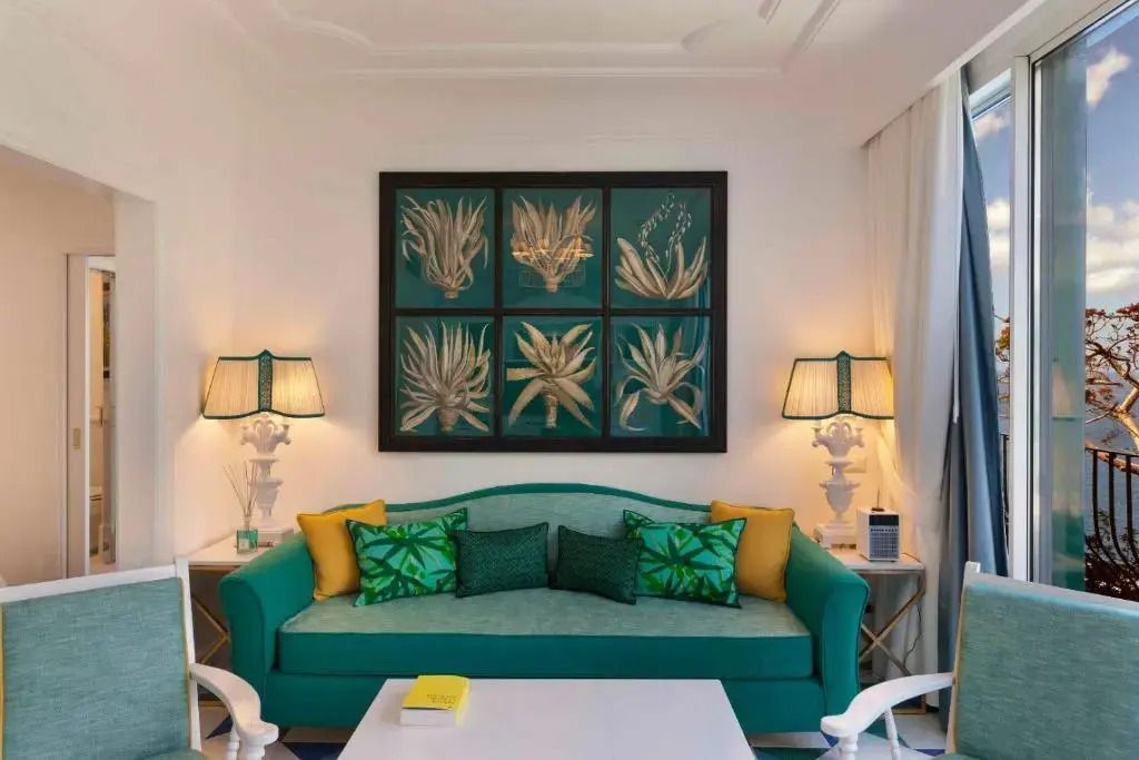 Wohnbereich mit grünem Sofa und stilvollen Kunstwerken an der Wand.