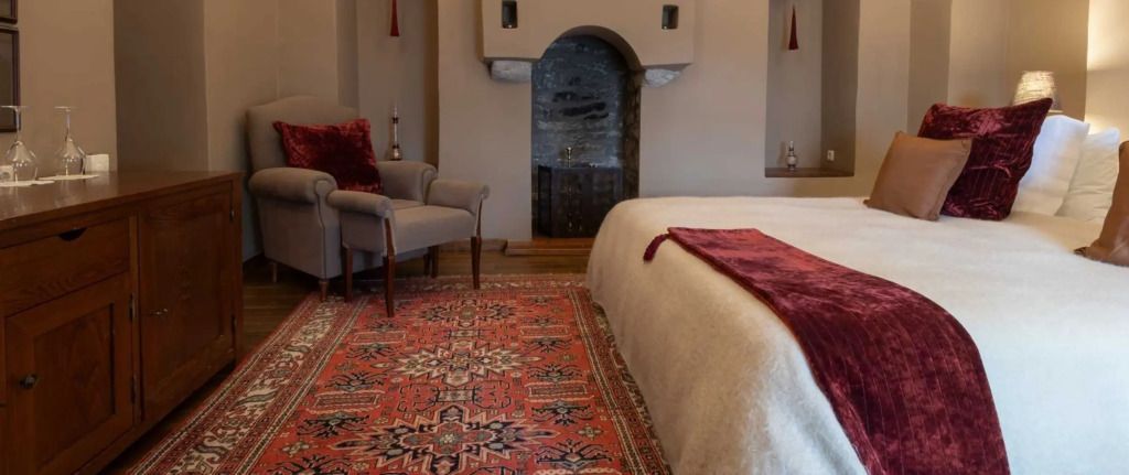 Gemütliches Hotelzimmer mit Teppich und Kamin neben einem Sessel