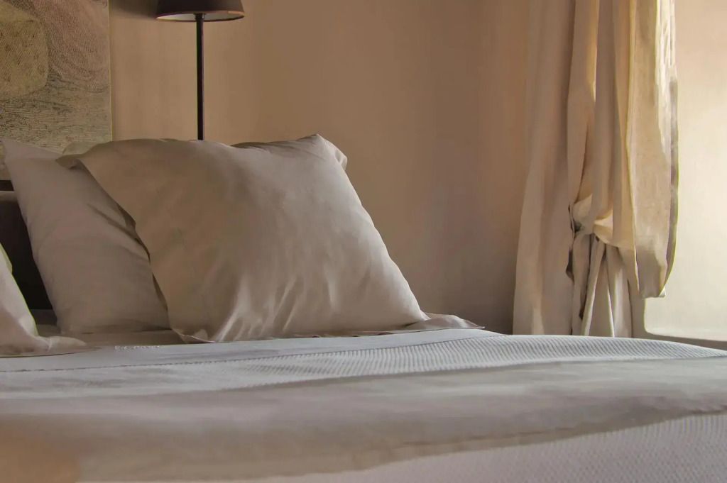 Gemütliches Bett mit eleganter Bettwäsche und sanfter Beleuchtung