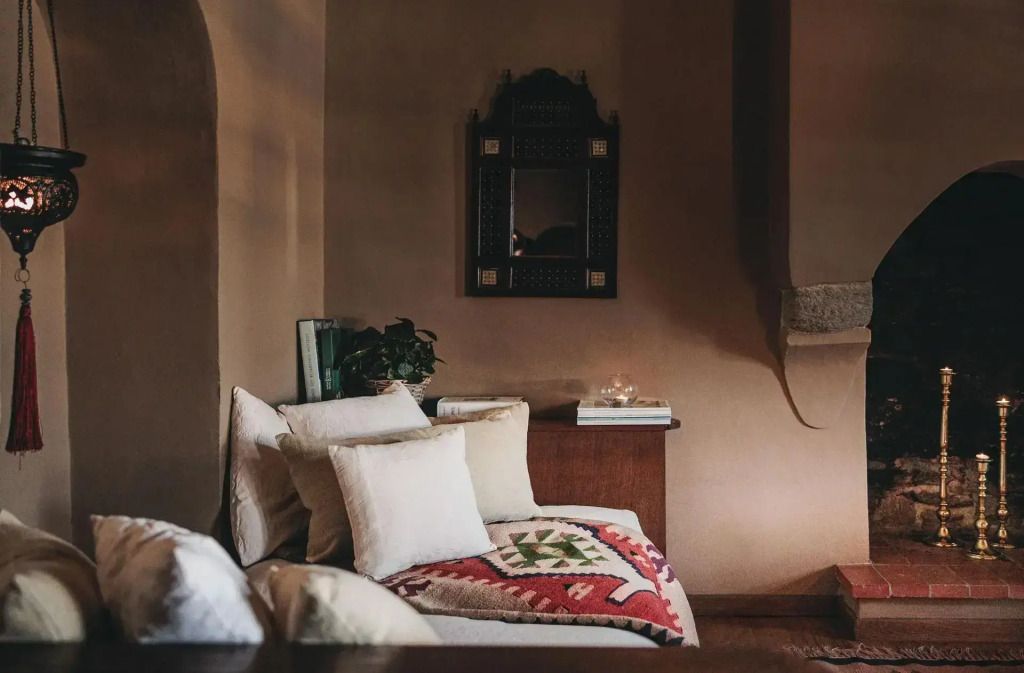 Gemütliche Sitzecke mit traditionellen Kissen und dekorativem Spiegel im Zimmer.