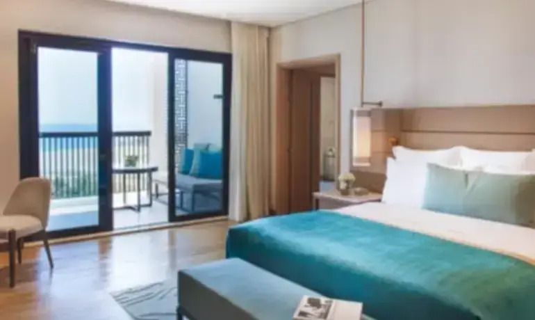 Helles Schlafzimmer in Suite mit Balkon und Meerblick, moderne Einrichtung.