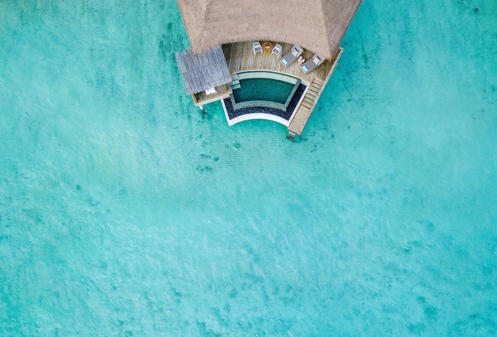 Luftaufnahme einer Villa mit Pool am türkisblauen Meer
