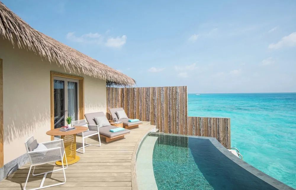 Terrasse mit Pool und Sonnenliegen direkt am hellblauen Meer