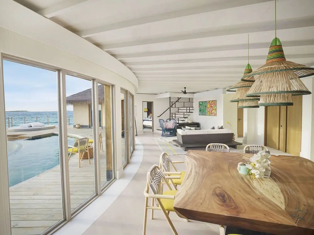 Großer Wohnbereich mit Holztisch und Zugang zur Terrasse am Pool