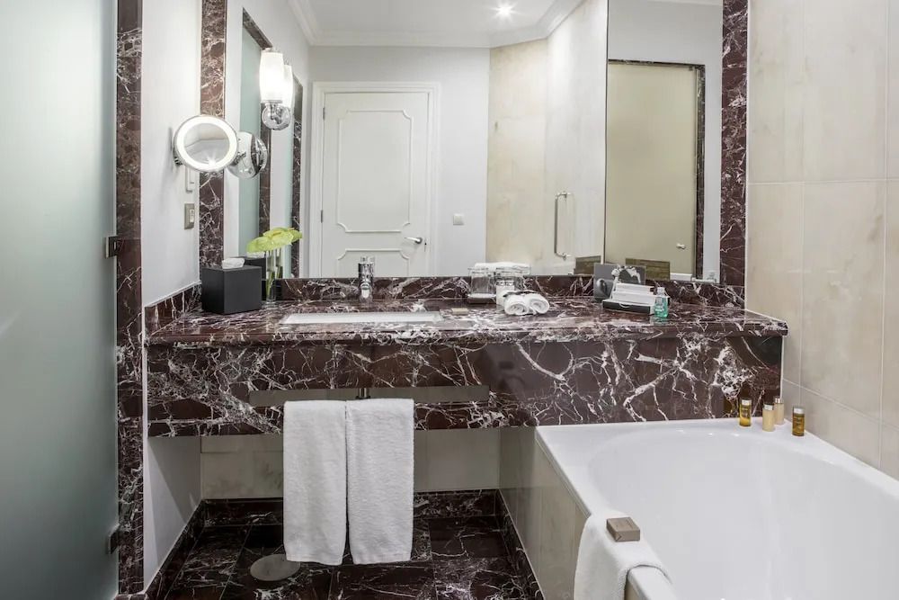 Badezimmer mit Marmorwaschtisch und Badewanne in der Junior-Suite.