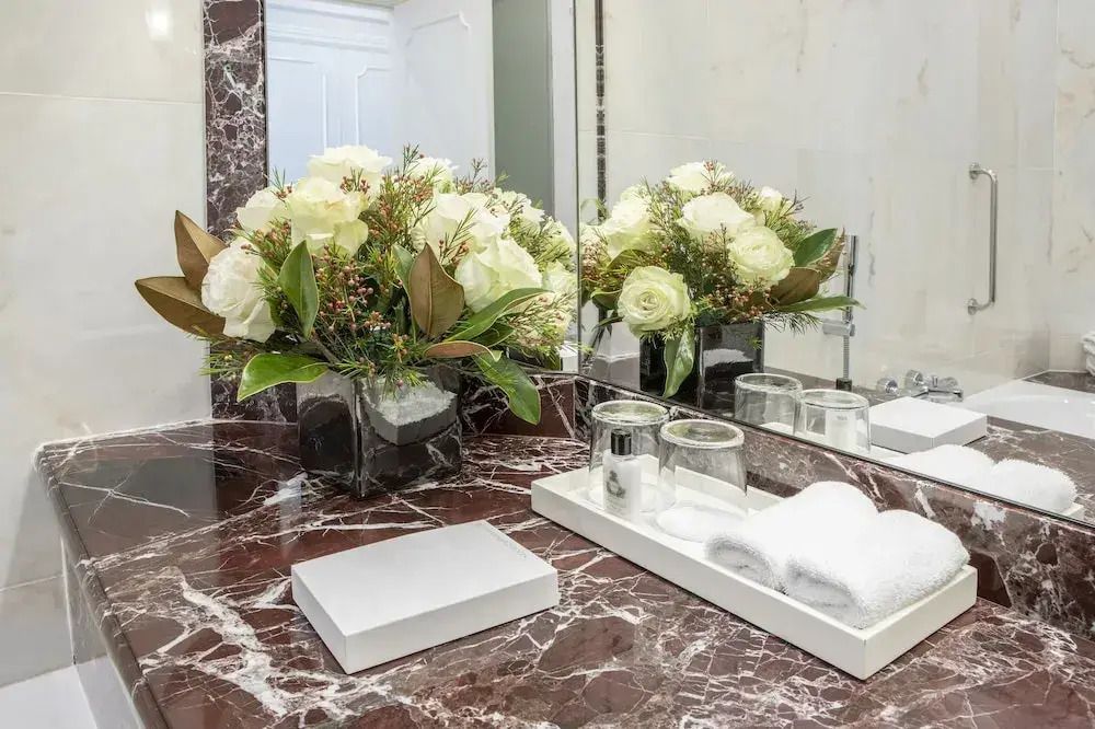Marmorwaschtisch mit Blumendekoration und Toilettenartikeln.