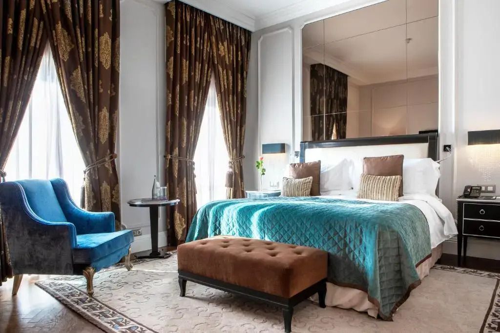 Luxuriöses Doppelbettzimmer mit prächtigen Vorhängen und blauen Akzenten.