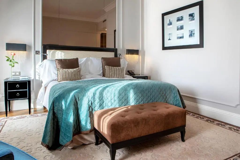Premium Doppelbett mit Sitzbank und Kunst an der Wand im stilvollen Hotelzimmer