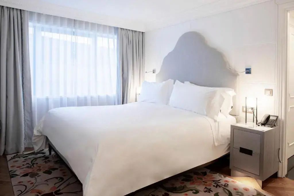 Schlafzimmer mit großem Doppelbett und eleganten Vorhängen