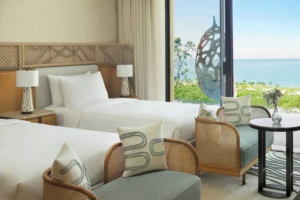 Doppelbettzimmer mit stilvollen Möbeln und großem Fenster mit Ausblick auf das Meer
