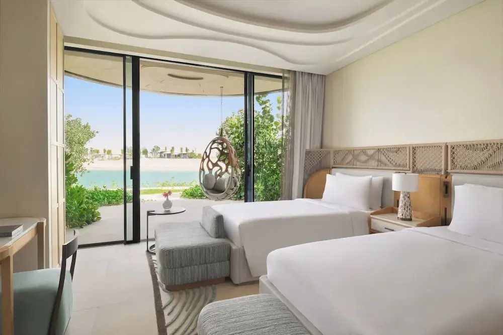 Zimmer mit zwei Einzelbetten und bodentiefer Fensterfront mit Meerblick.