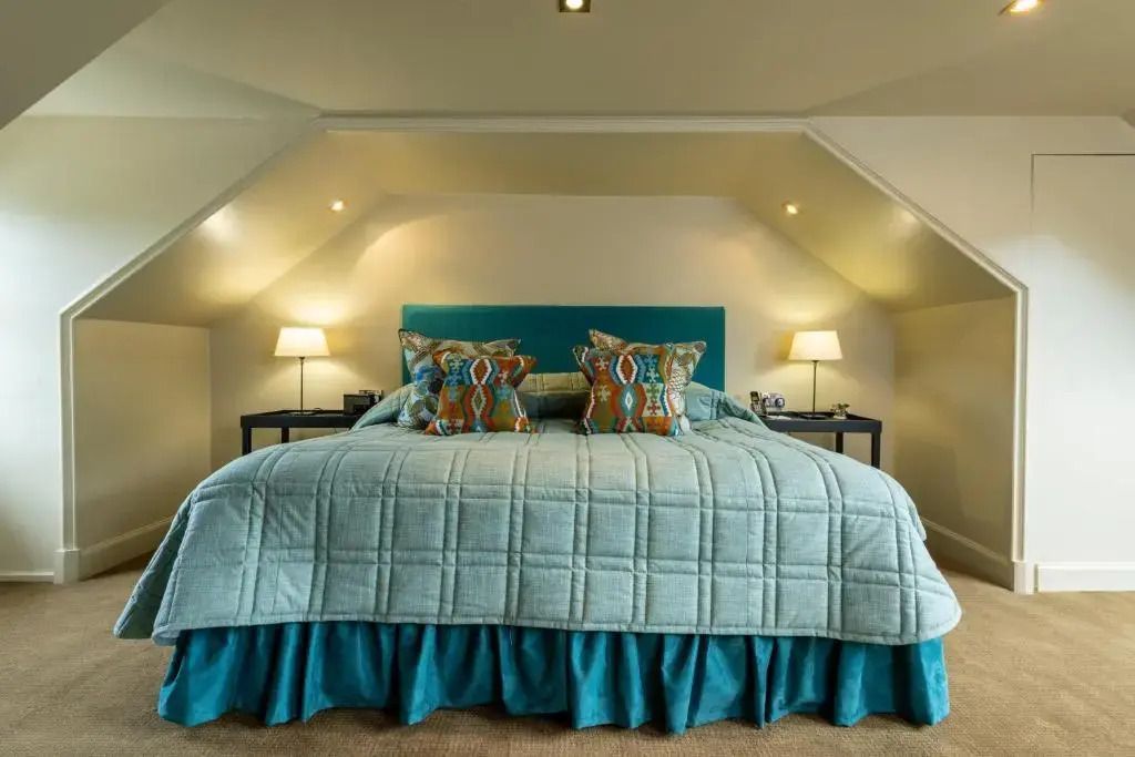 Gemütliches Doppelbett mit farbenfrohen Kissen in einer stilvollen Suite