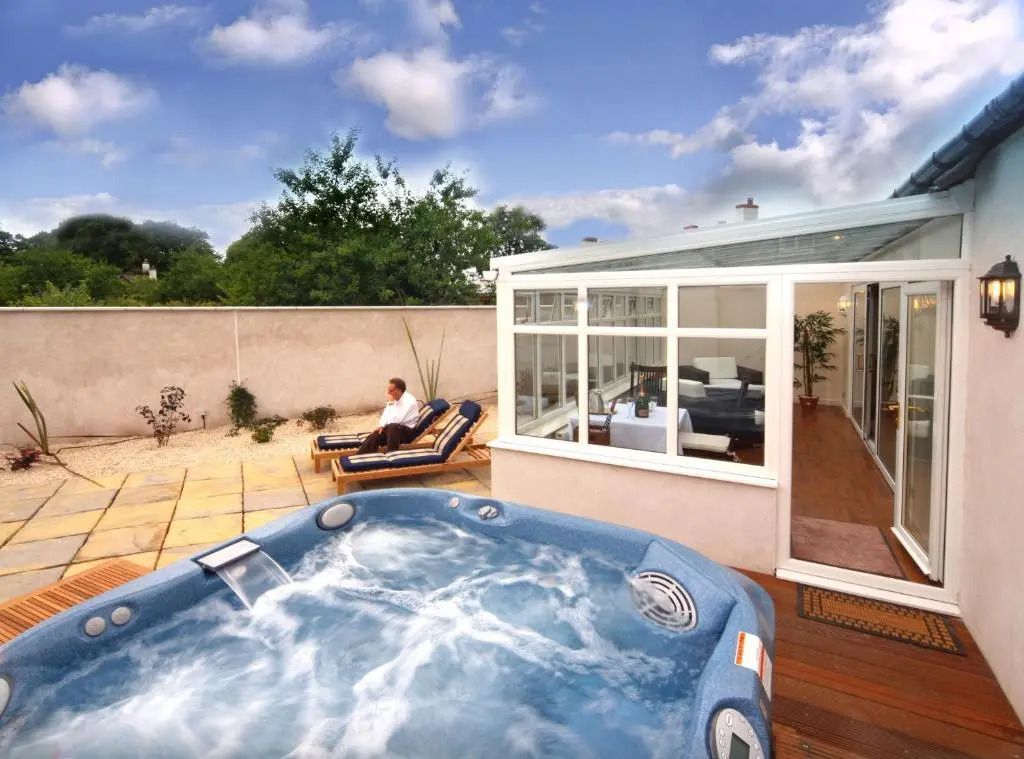 Whirlpool auf der Terrasse mit Fenstern zur Lounge und Blick auf den Garten