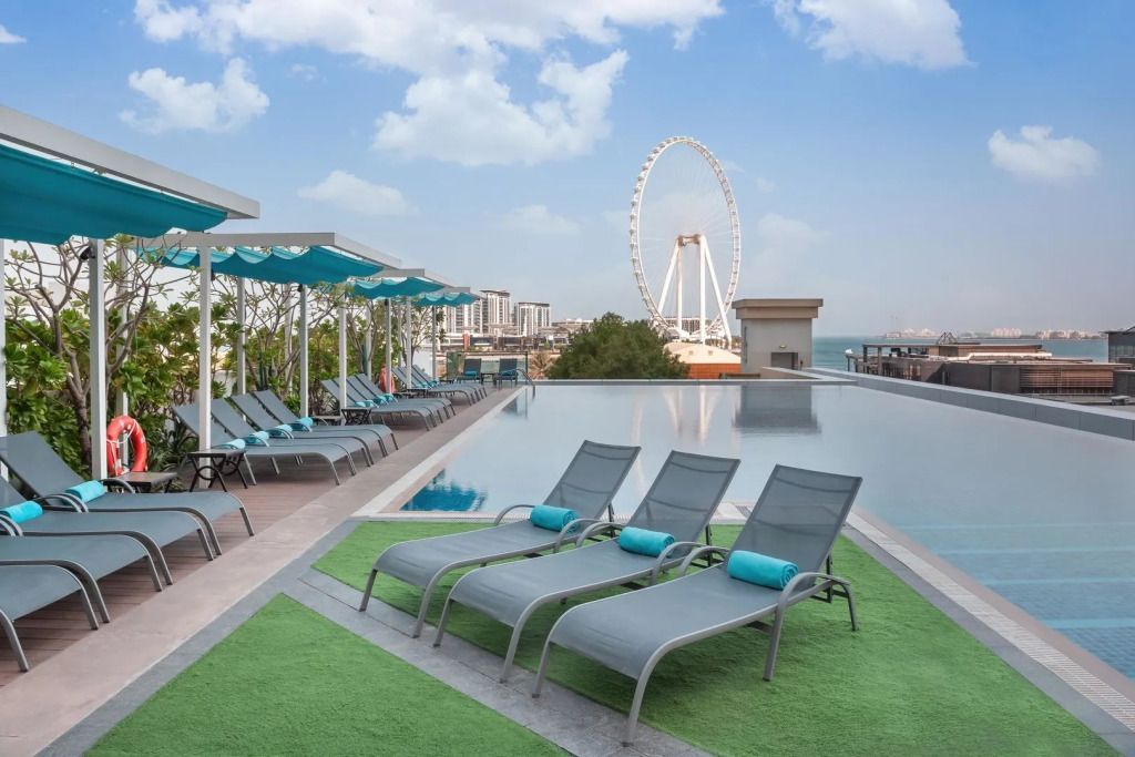 Sonnenliegen am Infinity-Pool mit Blick auf ein Riesenrad