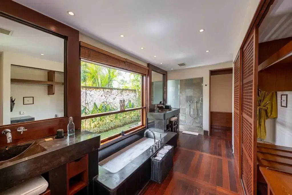 Modernes Badezimmer mit großer Badewanne und Gartenblick.