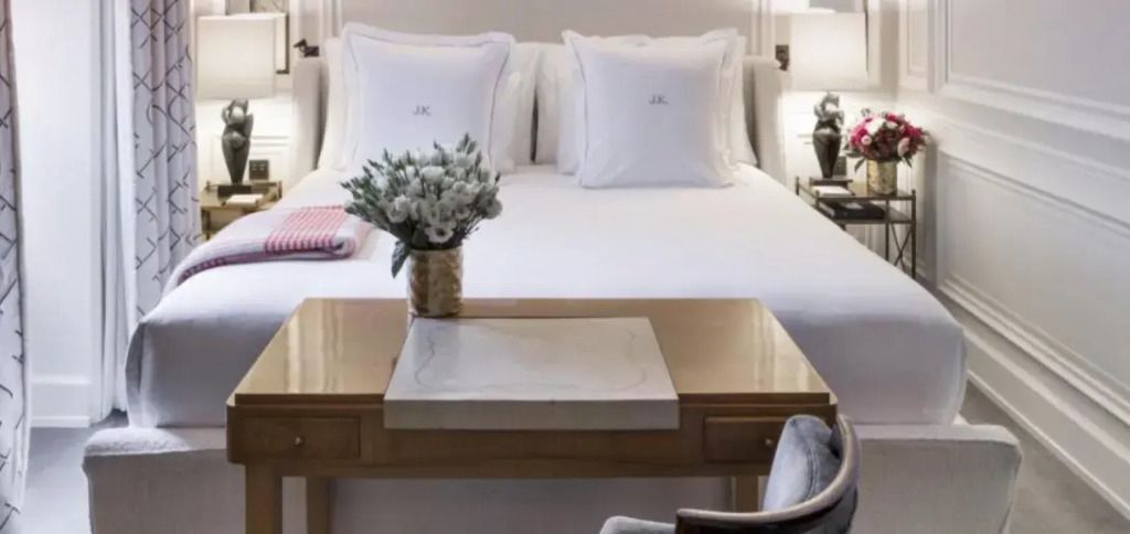 Doppelbett mit weißen Kissen und frischen Blumen auf einem Holztisch