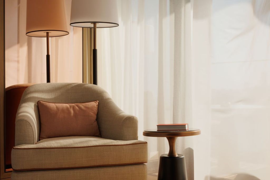 Gemütliche Sitzecke mit Sessel und Beistelltisch in warmem Licht im Deluxe Zimmer.
