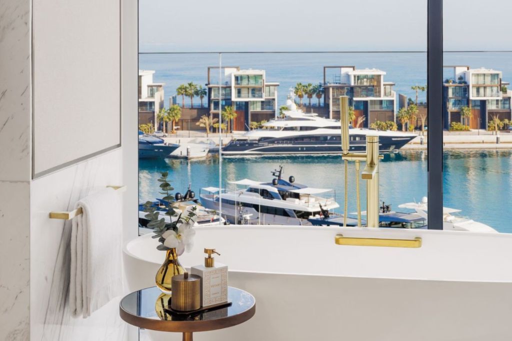Luxuriöses Badezimmer mit freistehender Wanne und Panoramablick auf den Yachthafen.