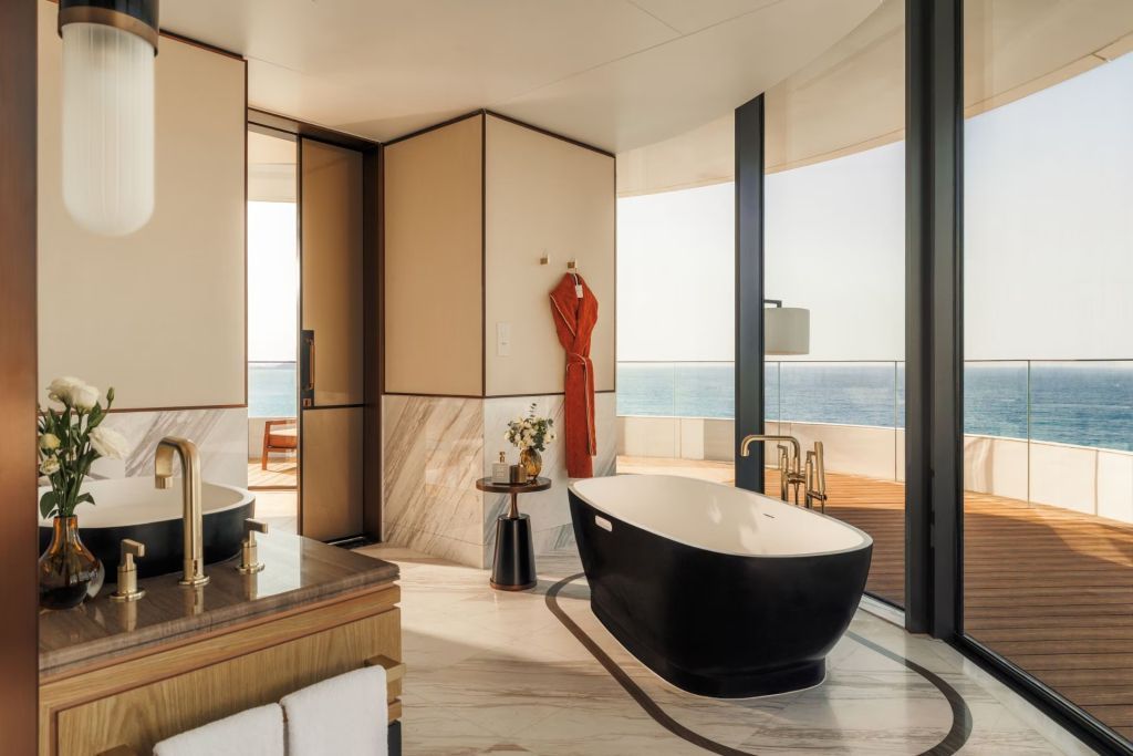 Luxuriöses Badezimmer mit freistehender Badewanne und Blick auf das Meer