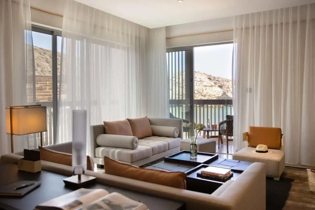 Gemütliches Wohnzimmer der Suite mit großen Fenstern und Blick auf die Landschaft.