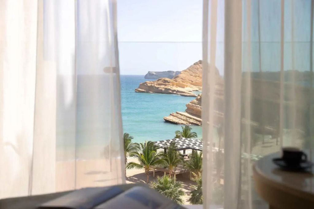 Atemberaubender Meerblick von der Suite mit Palmen und Klippenlandschaft.