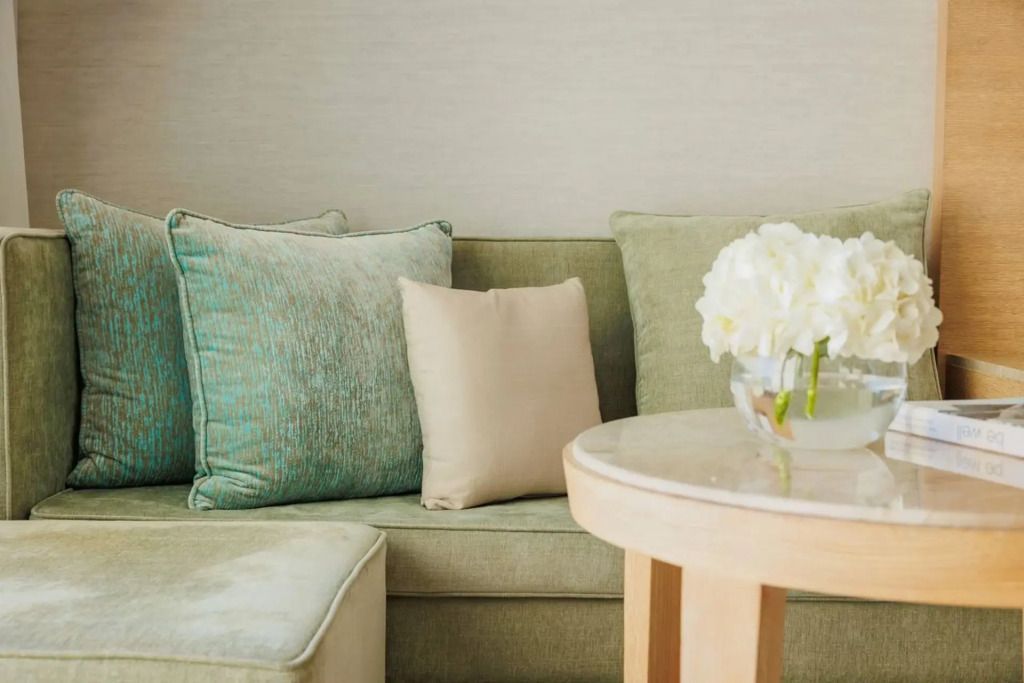 Detailaufnahme eines Sofas mit dekorativen Kissen und Blumen