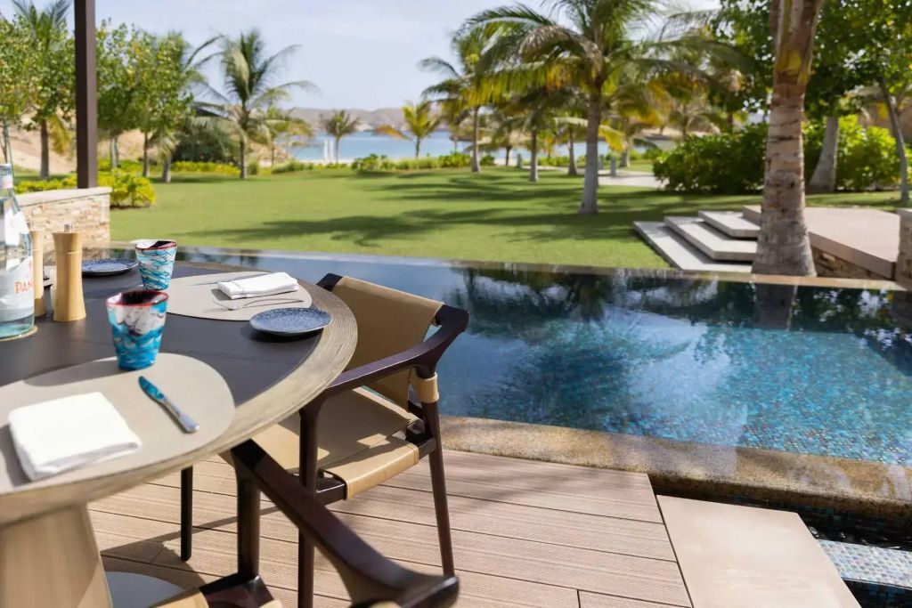 Terrasse mit Blick auf den Pool und Palmen gesäumt, im Garten des Resorts.