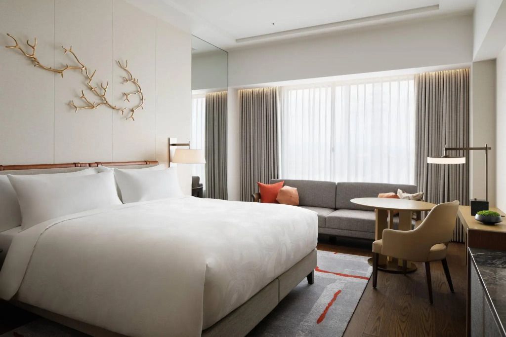 Elegantes Hotelzimmer mit Doppelbett, großem Fenster und gemütlichem Sitzecke