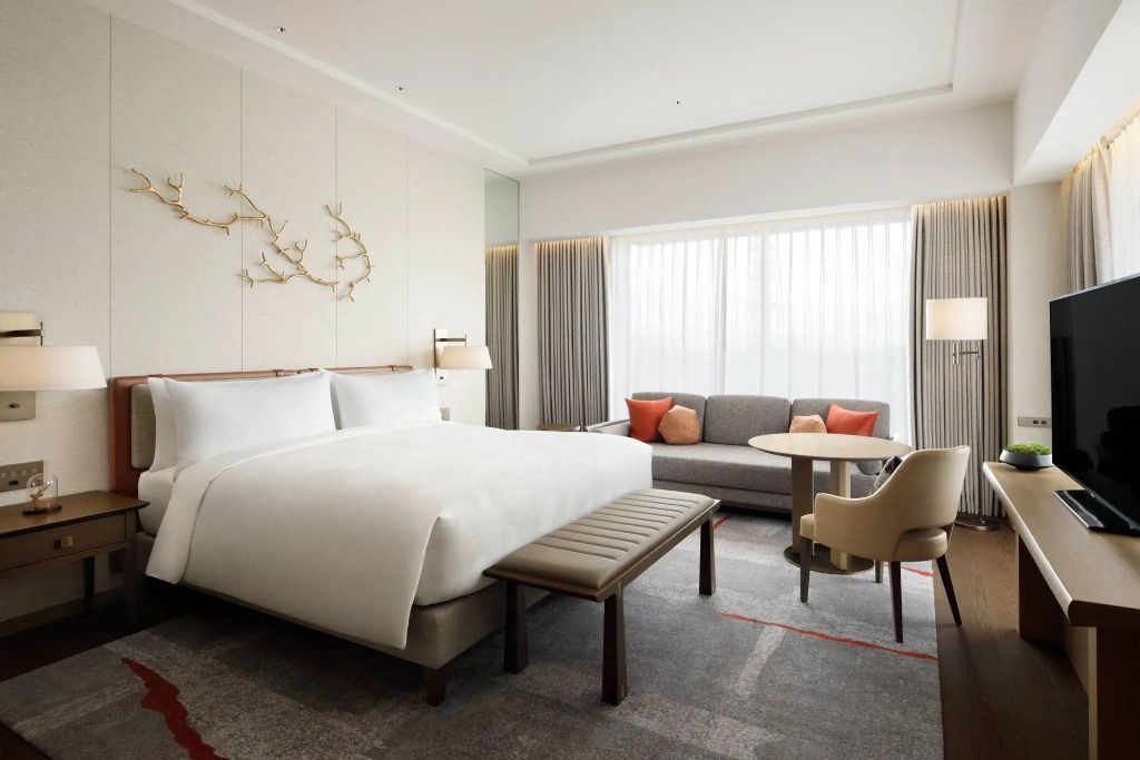 Geräumige Junior-Suite mit Doppelbett, Sofa und großem Fenster mit Stadtblick