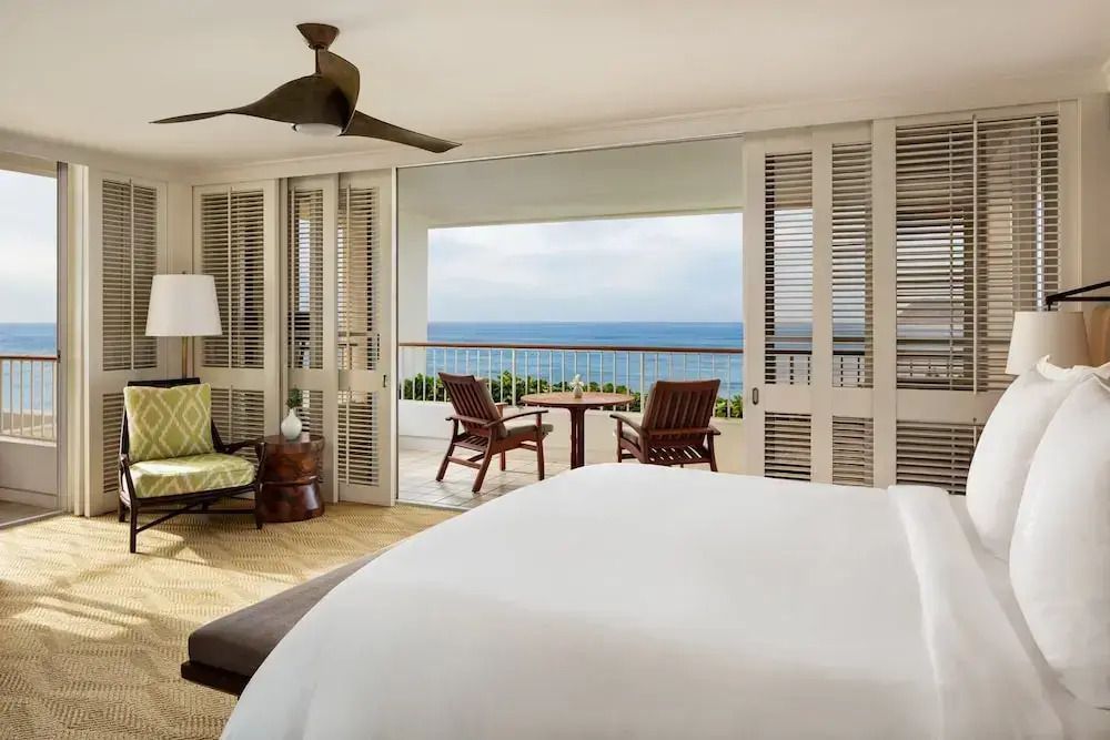 Schlafbereich der Suite mit großem Bett und Balkon mit Meerblick