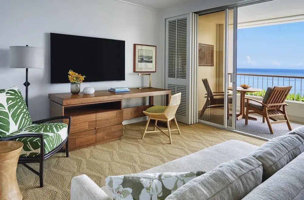 Wohnbereich der Suite mit Schreibtisch, Fernseher und Zugang zum Balkon