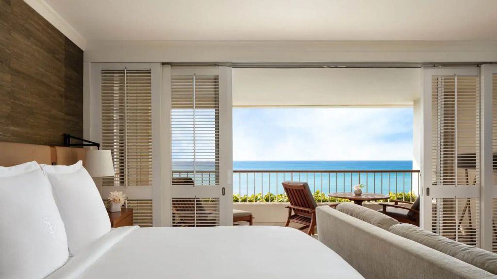 Helles Schlafzimmer mit Balkonblick auf das azurblaue Meer im Four Seasons Resort.