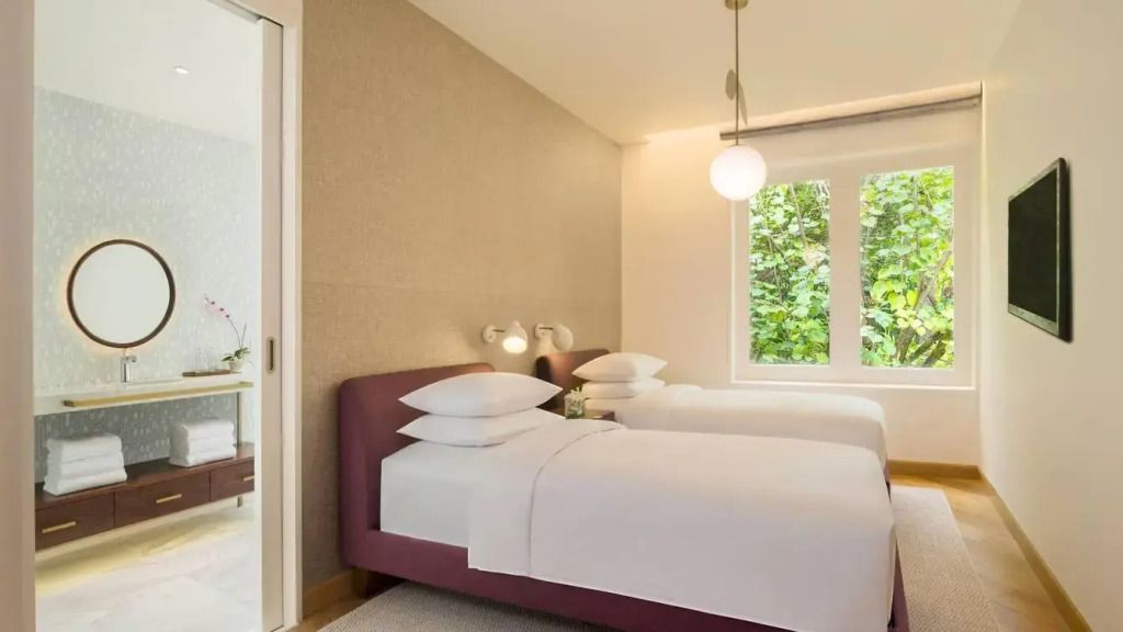Helles Schlafzimmer mit zwei weißen Einzelbetten und minimalistischer Einrichtung