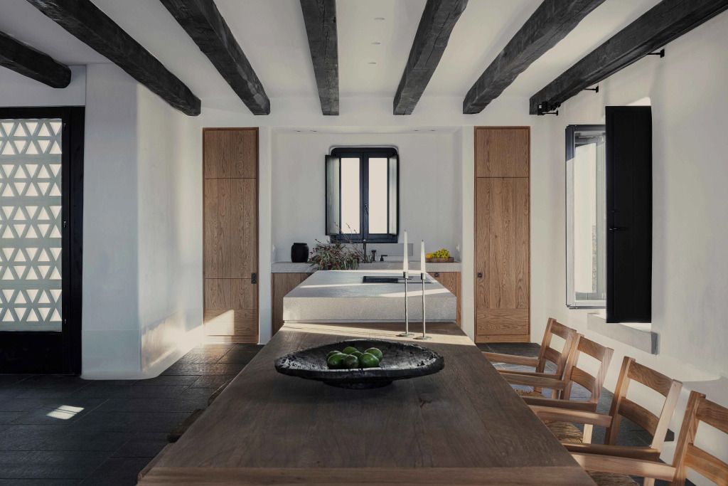 Moderne Küche in einer Villa mit Holzbalken, Esstisch und viel natürlichem Licht