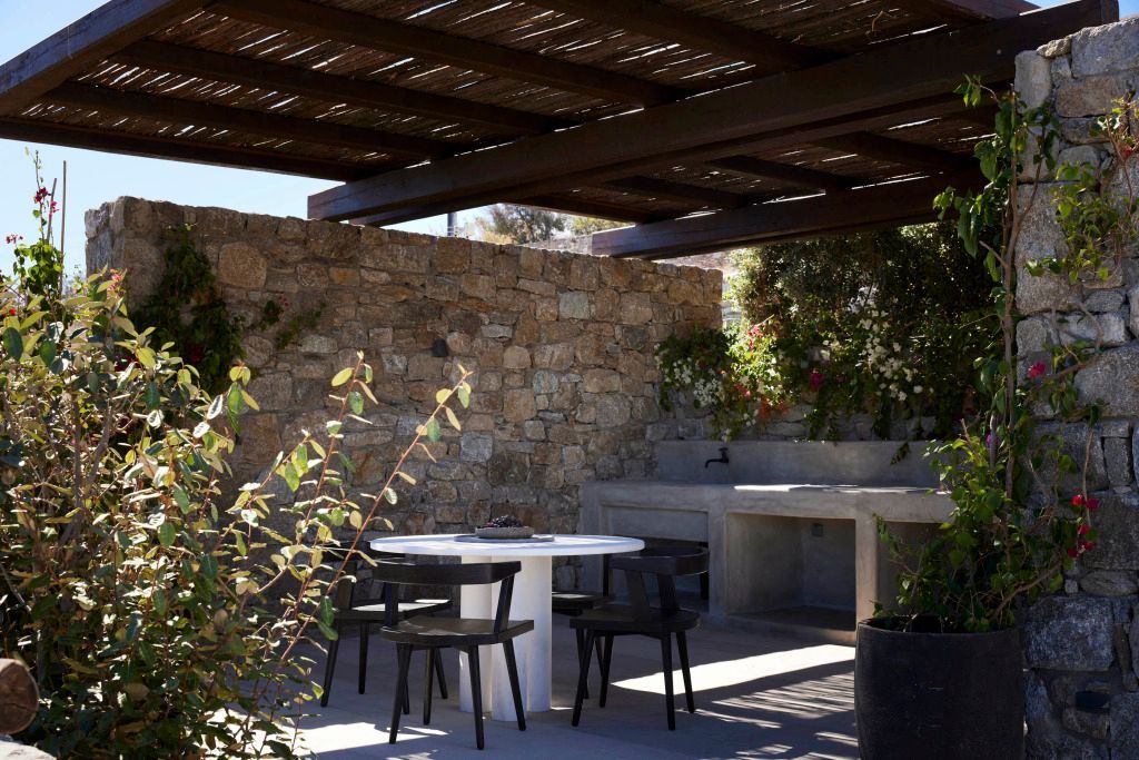 Schattige Terrasse mit Holzdach und rundem Tisch aus Stein im Freien