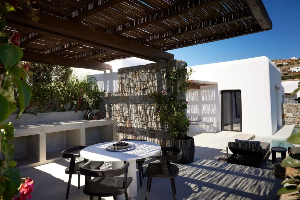 Steinterrasse mit Pergola und modernem Tisch und Stühlen im Freien