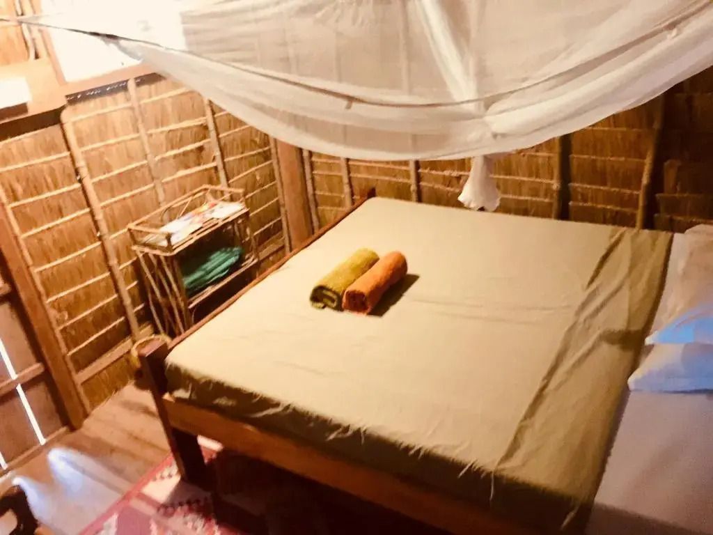Interieur eines Bungalows mit großem Bett und Moskitonetz
