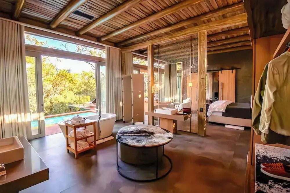 Luxuriöses Schlafzimmer mit freistehender Badewanne und Blick auf den privaten Pool