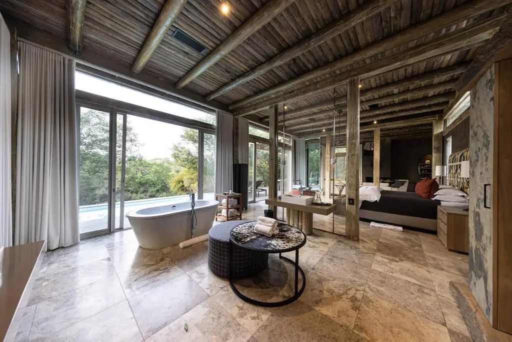Geräumige Suite mit freistehender Badewanne und großen Fenstern mit Blick ins Grüne