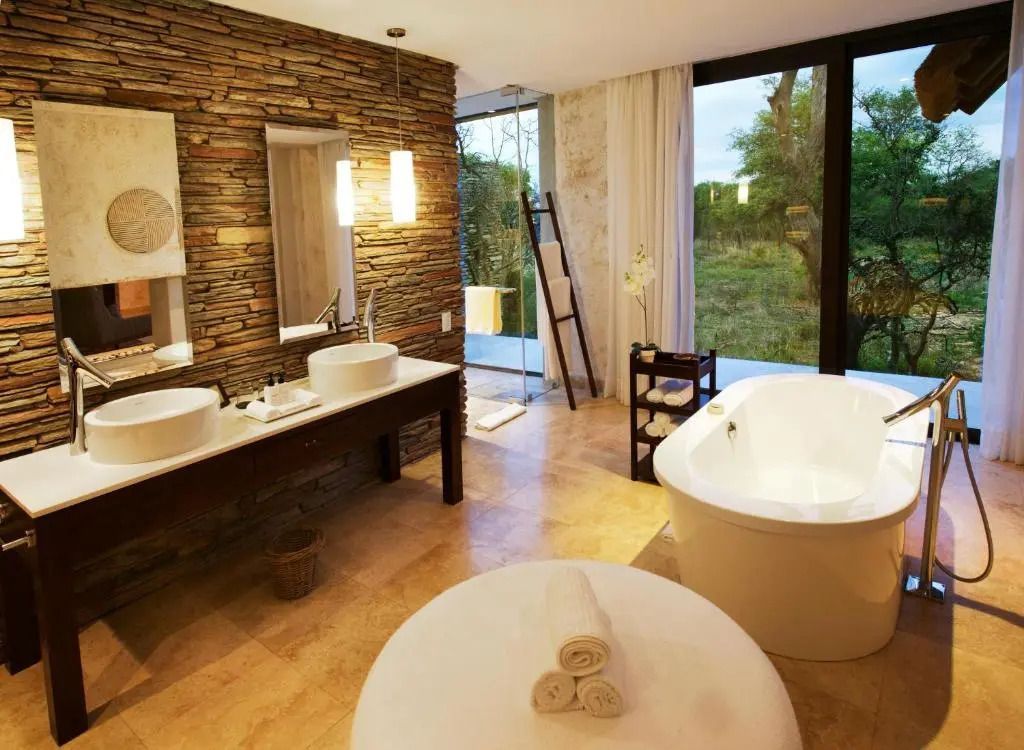 Luxuriöses Badezimmer mit freistehender Badewanne und Blick ins Grüne