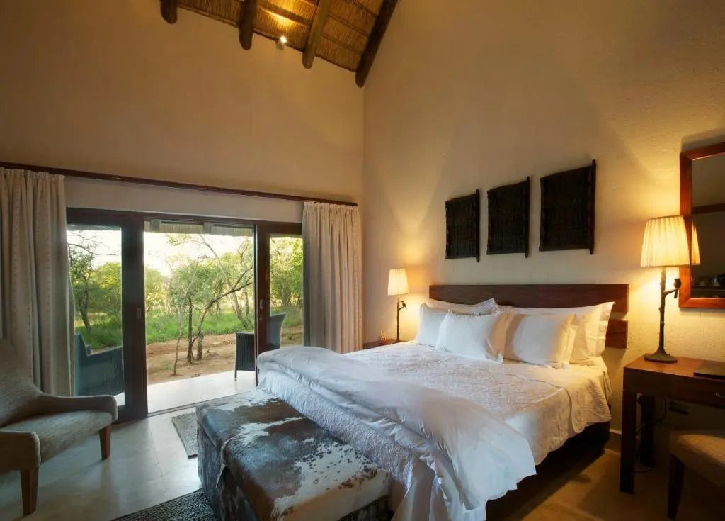 Elegantes Schlafzimmer mit Doppelbett und Zugang zur Terrasse mit Gartenblick