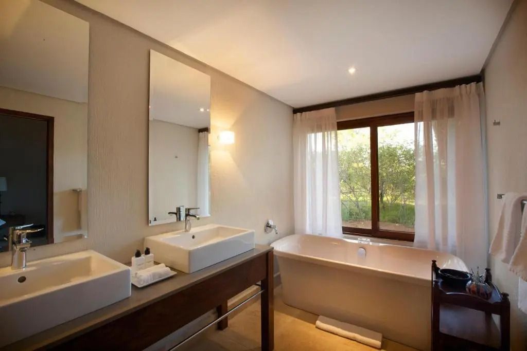 Moderne Badezimmerausstattung mit Badewanne und Blick in den Garten