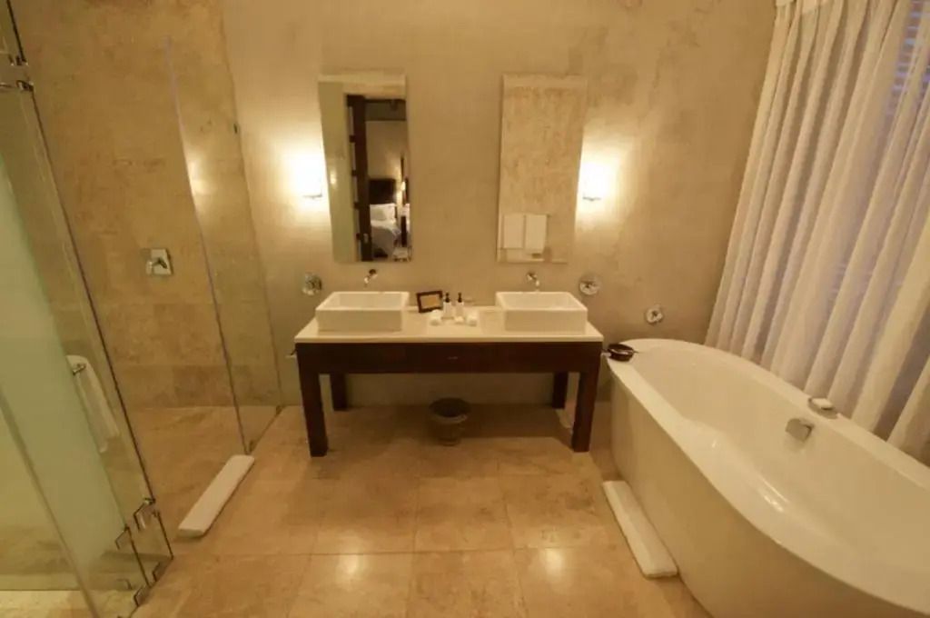 Helles Badezimmer mit Doppelwaschbecken, freistehender Badewanne und Duschbereich.